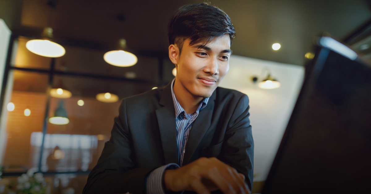 A Filipino man sits at the table looking at his laptop reading about the UK visa for Filipinos process