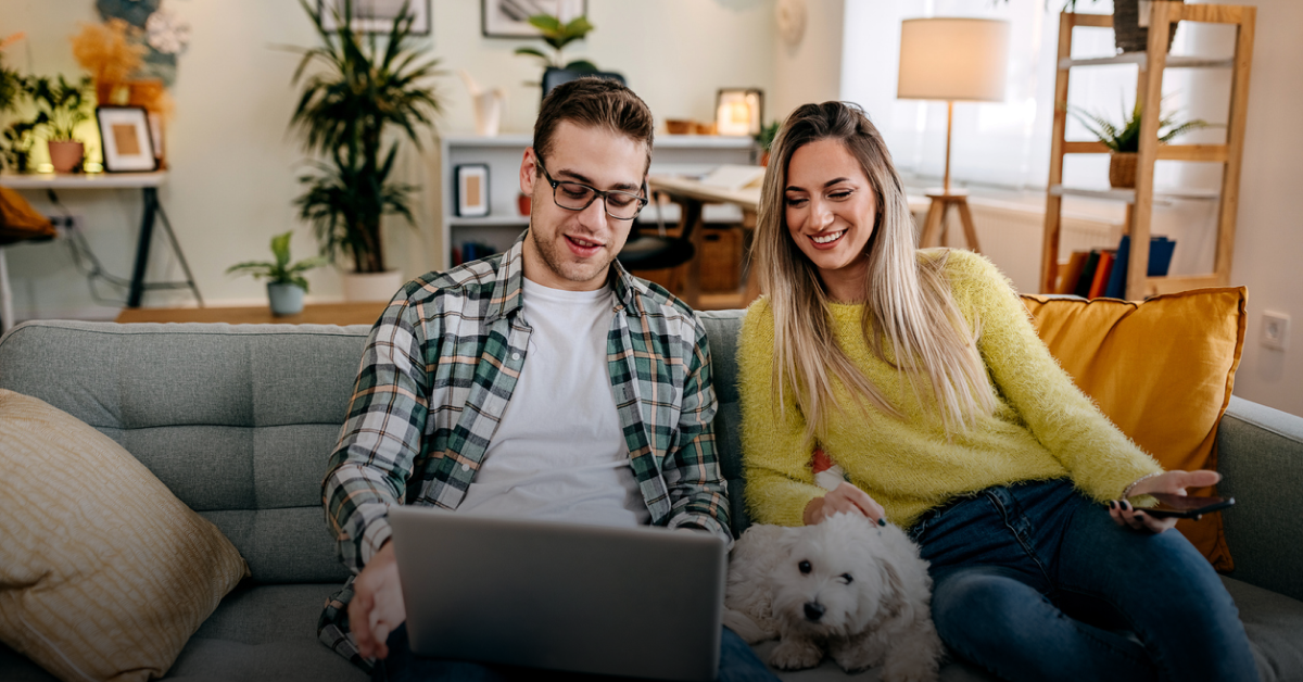 A young man and woman sit on a sofa and look at a laptop reading about the best Wise alternatives