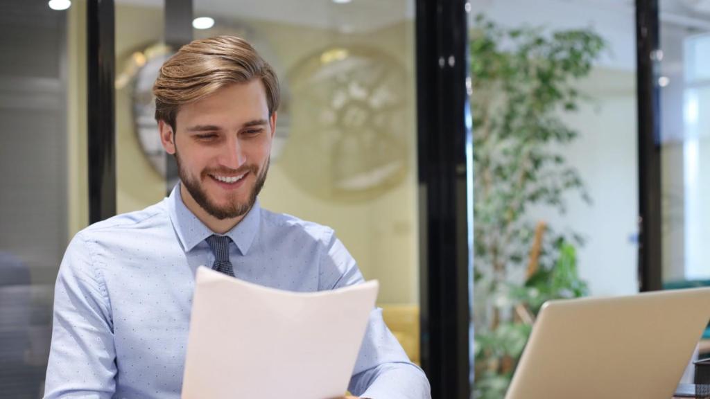 A young man in a pale blue suit and tie reads a paper on how to 'register company Lithuania' 