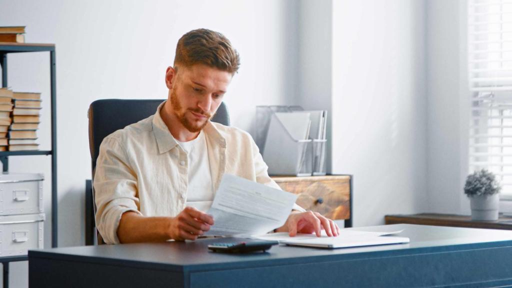 A young male sits at a desk, reading a guide on how to register company in Lithuania