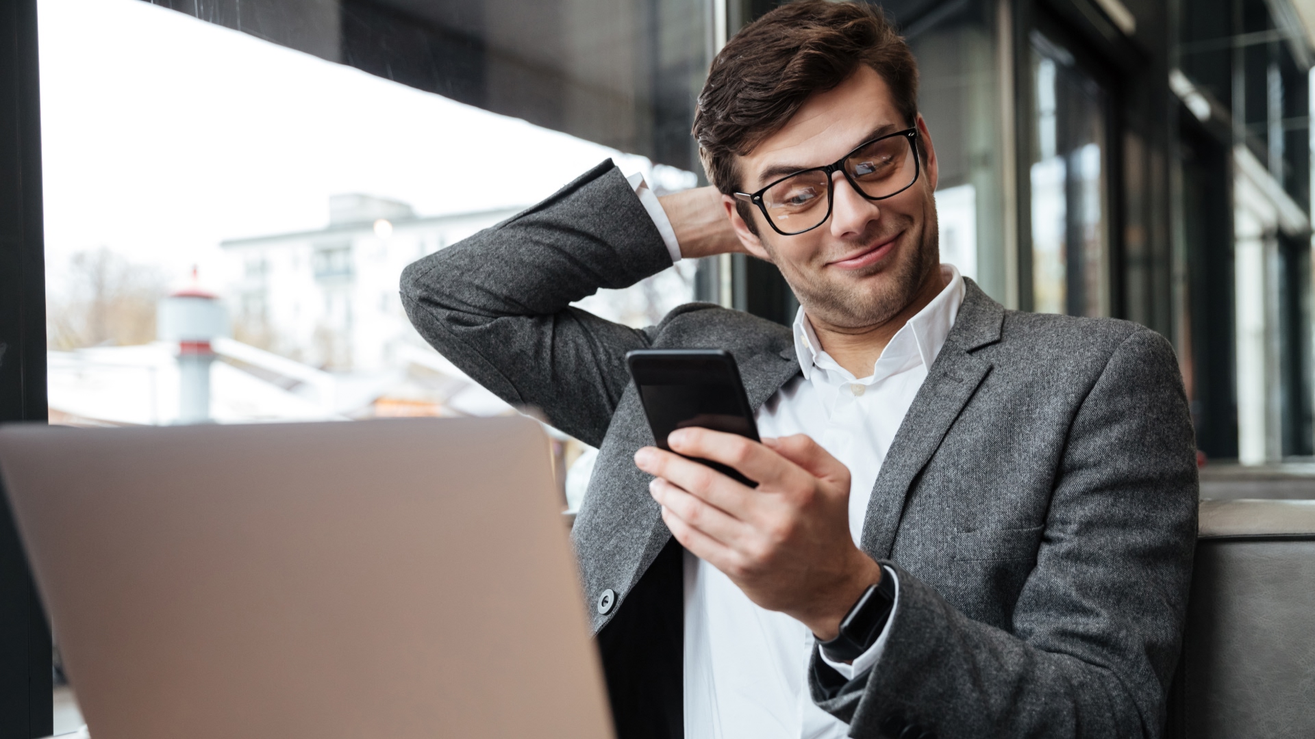 A young, white male in a suit reads an article on his phone about how to open a Lloyds Bank Business Account.